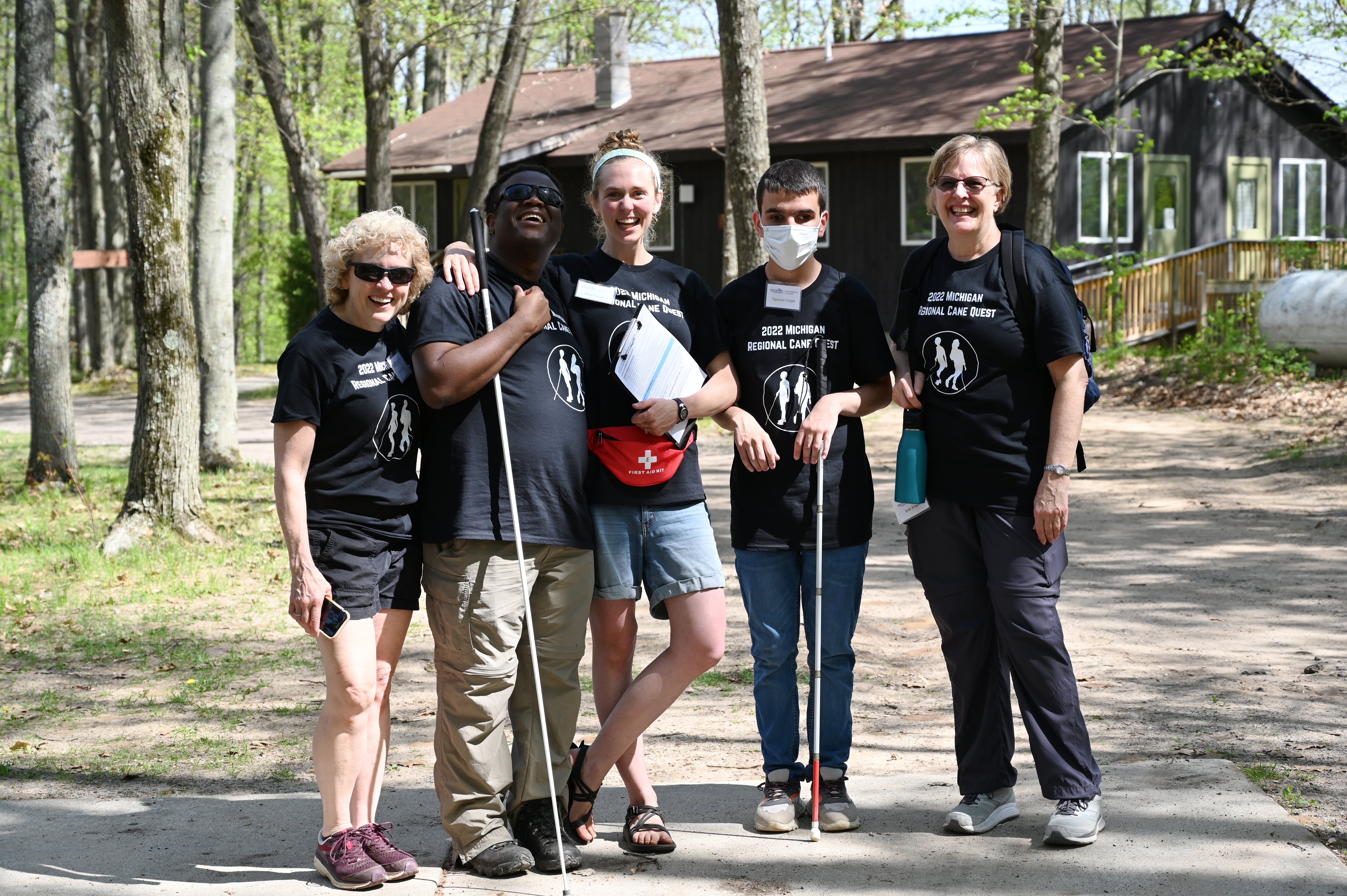 Five Cane Quest volunteers smile for a photo outside at Camp T.