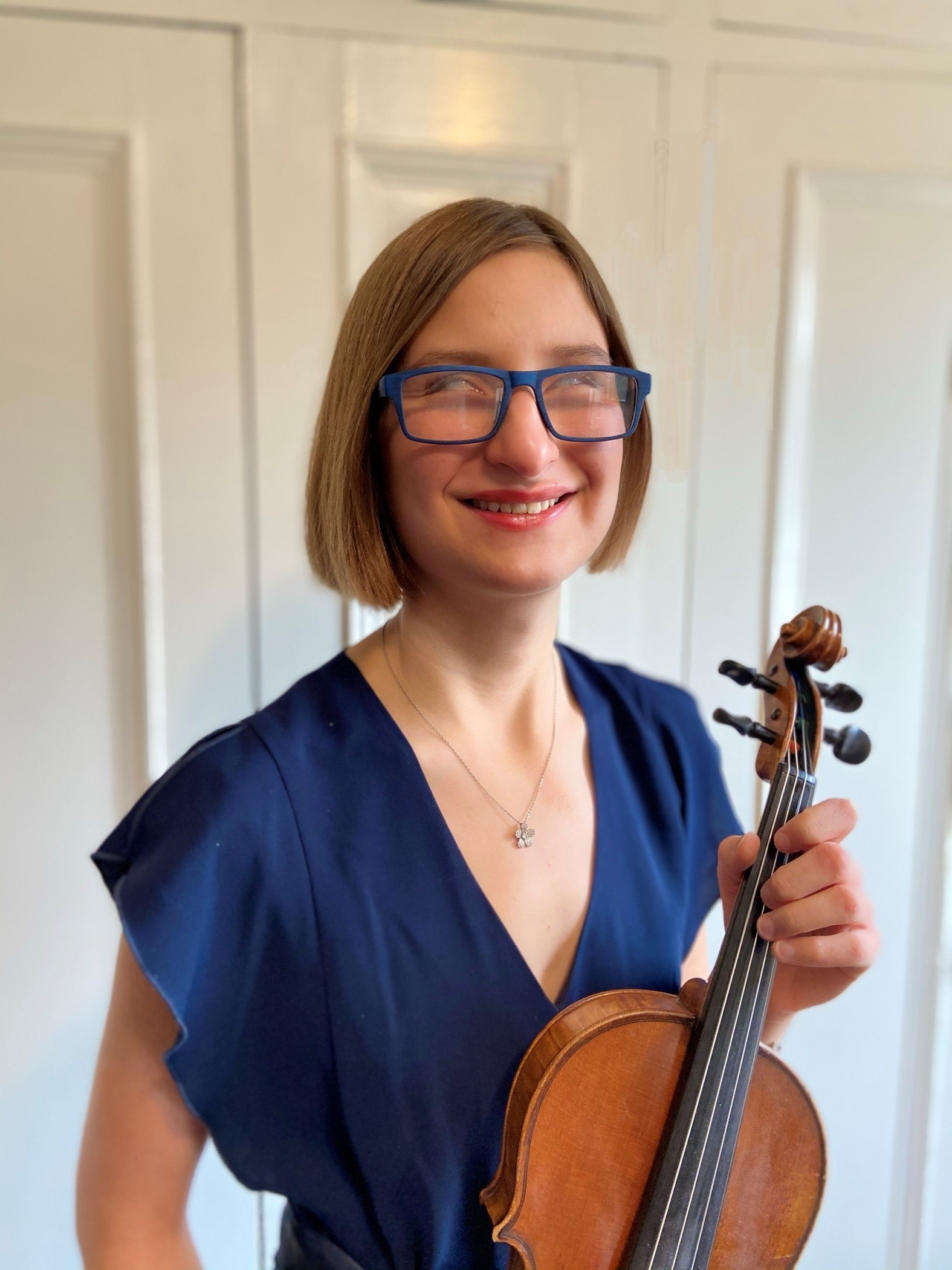 Julia smiles for a photo while holding her violin.