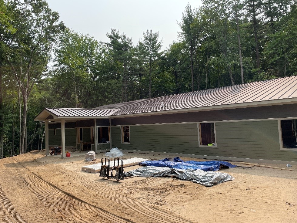 The front of the nature center features large windows, a covered entryway, and green and brown siding.