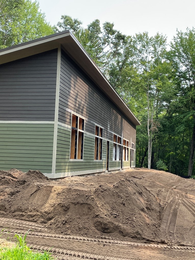 The side of the nature center features several large windows, a slanted roof, and green and brown siding.