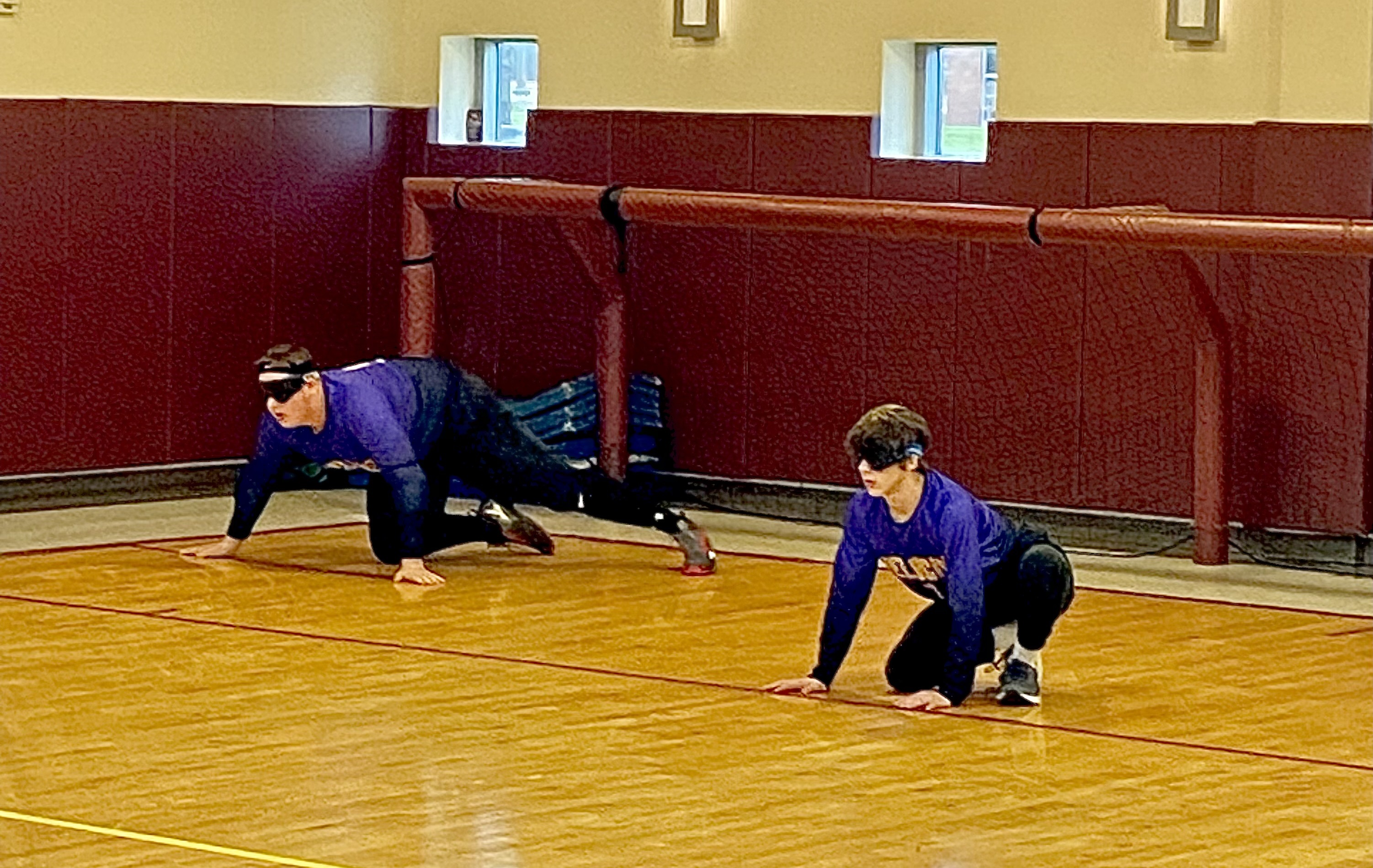 Two goalball players prepare to block a ball from going into the net.