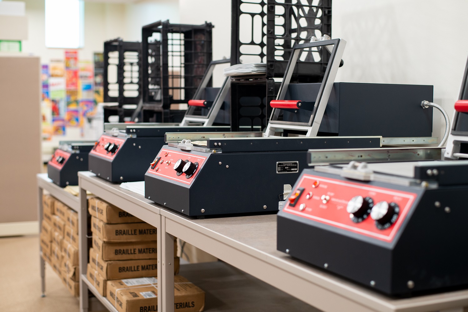 A row of four square black and red thermoform machines with a switch and two large knobs on the front.
