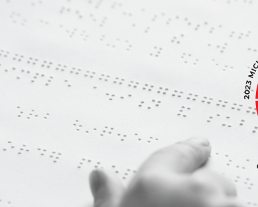 Closeup of someone reading braille. The Michigan Regional Braille Challenge logo, Challenge Your Limits, is on the right side.