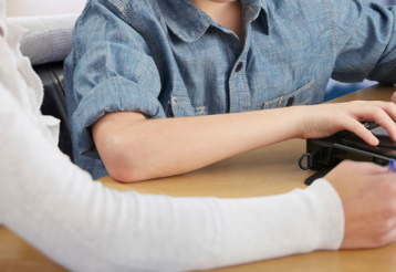A teen uses a BrailleNote Touch while an instructor watches. 