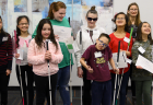 Twelve students, ranging from elementary to high school age, smile for a group photo. Most of the students are holding white canes.