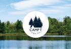 The lake at Camp T surrounded by pine trees on a sunny day. The Camp T logo is on the image.