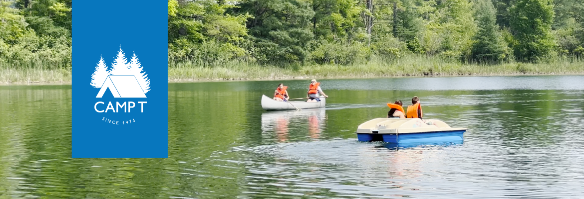 Two campers in a canoe and two campers in a paddle boat on Flanagan Lake at Camp T.