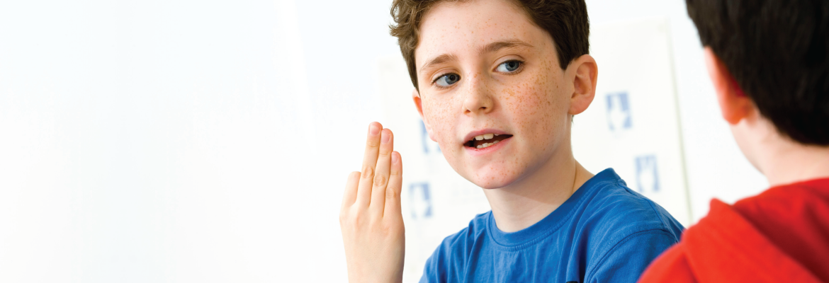 A young boy signs to communicate with another child.