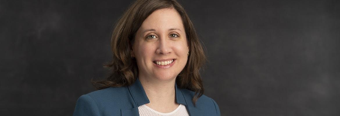 Elizabeth Flores, wearing a blue blazer, smiles for a professional headshot.