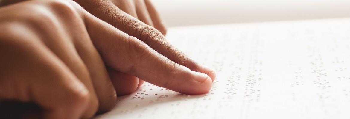 Closeup of a person's hands reading a line of braille.