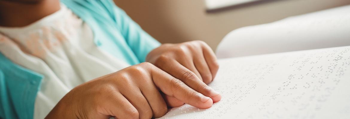 Closeup of a young girl reading a book in braille.