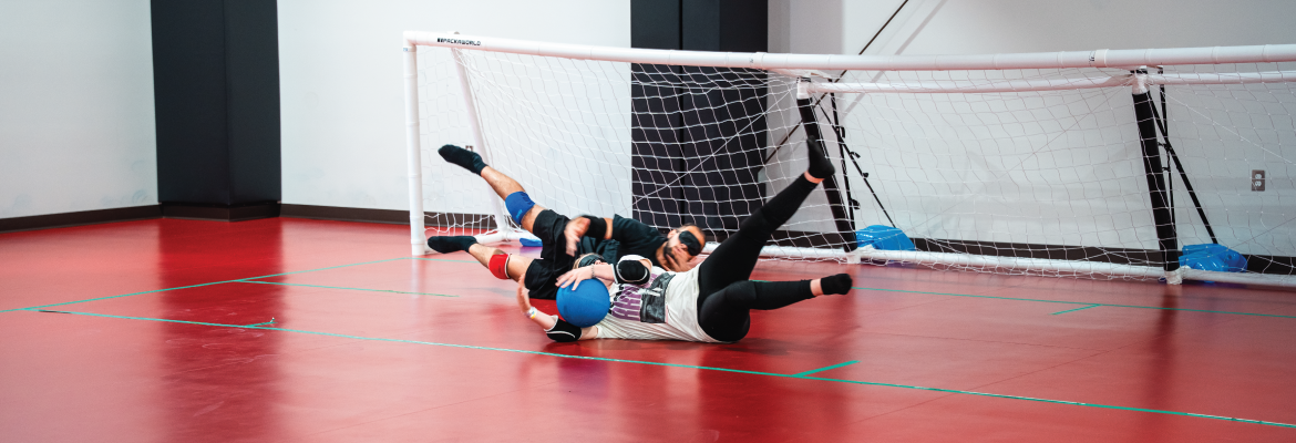 Two players dive for and catch a ball while playing goal ball.