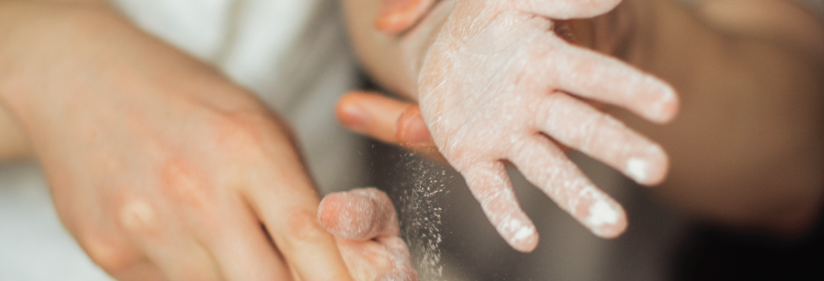 Closeup of an adult helping a child bake. Flour is on the child's hands.