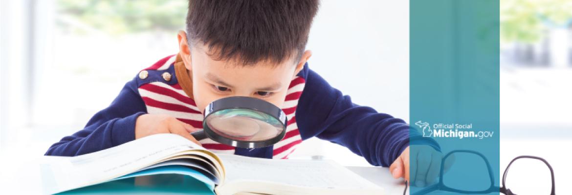 A boy with a magnifying glass reading a book