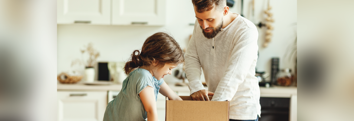 A man and his daughter opening a brown box in a kitchen.