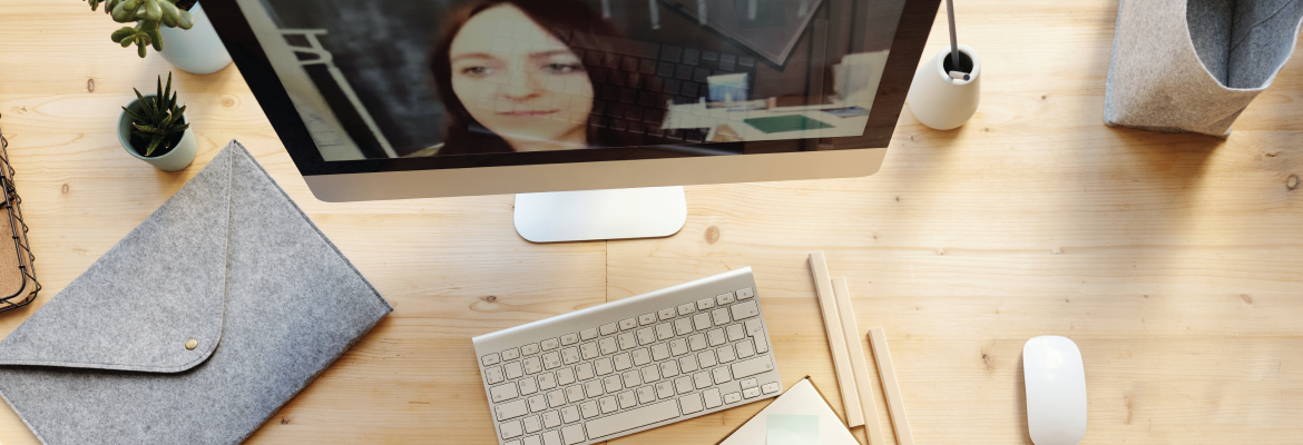 Overhead view of someone at a desk who is writing in a notepad while in an online meeting.