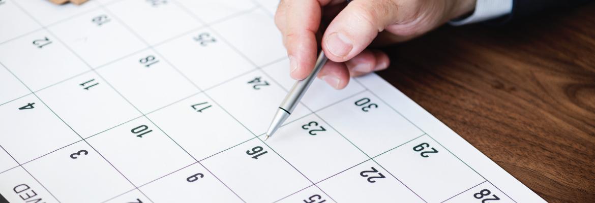 A person pointing at a calendar