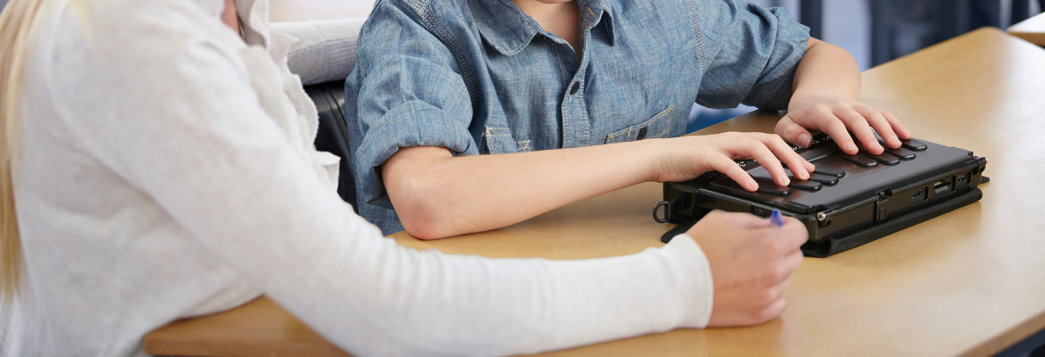 A teen uses a BrailleNote Touch while an instructor watches.