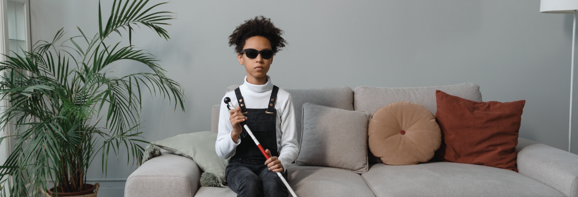 A girl wearing glasses and holding a white cane