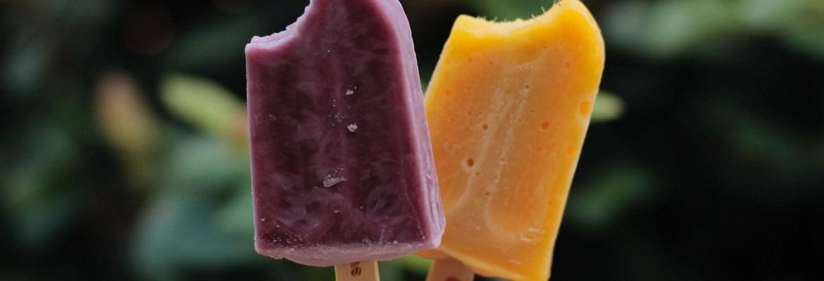 A purple popsicle and orange popsicle, with a bite taken out of each.