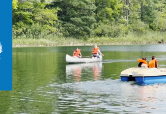 Two campers in a canoe and two campers in a paddle boat on Flanagan Lake at Camp T.