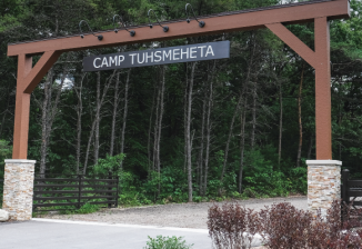 The entrance arch at Camp Tuhsmeheta, featuring wooden beams and the camp's name.