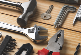Tools laid out on a workbench such as a hammer, screwdriver, pliers, and wrenches.
