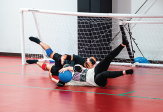 Two players dive for and catch a ball while playing goal ball. 