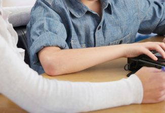 A teen uses a BrailleNote Touch while an instructor watches. 