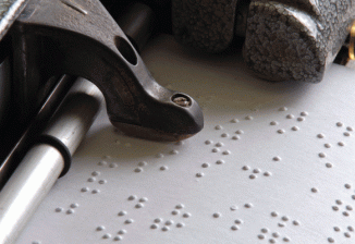 Closeup of a braille writer embossing braille onto a page.