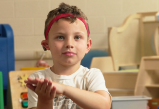 A student in a classroom using American Sign Language. 