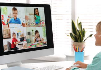 A young child smiles while in a video call with several other children.