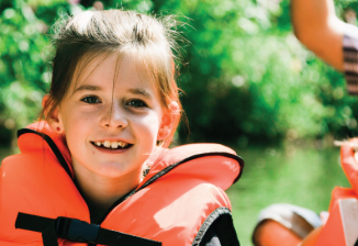 Two young girls wear life jackets while in a canoe with their parents.