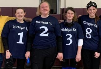 A group photo featuring four members of the girls' Michigan goalball team wearing their uniforms, along with their two coaches.
